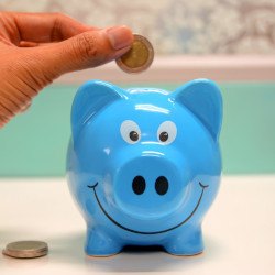 Hand putting coin in blue piggy bank