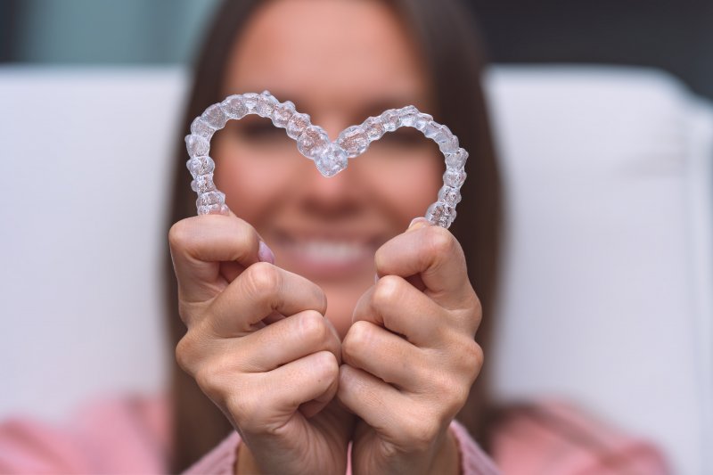 young woman making heart with Invisalign aligners