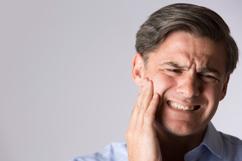 person with a dental emergency holding their cheek