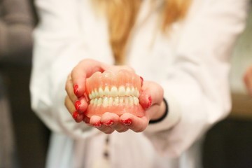 person smiling and holding dentures 
