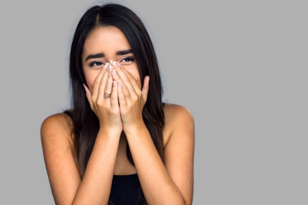 A teenage girl covering her mouth from embarrassment.